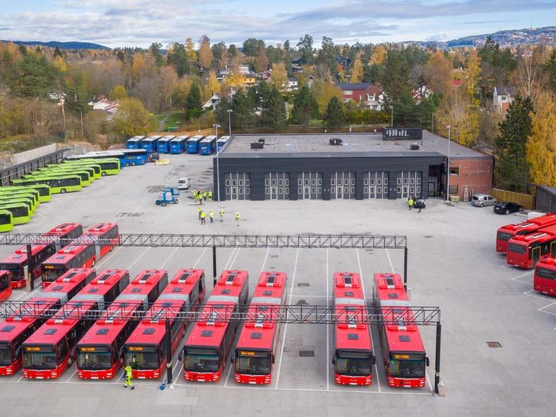 oversiktsbilde av bussanlegg med røde, grønne og blå farget busser